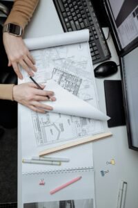 High-angle view of an architect reviewing construction drawings on a desk in an office.